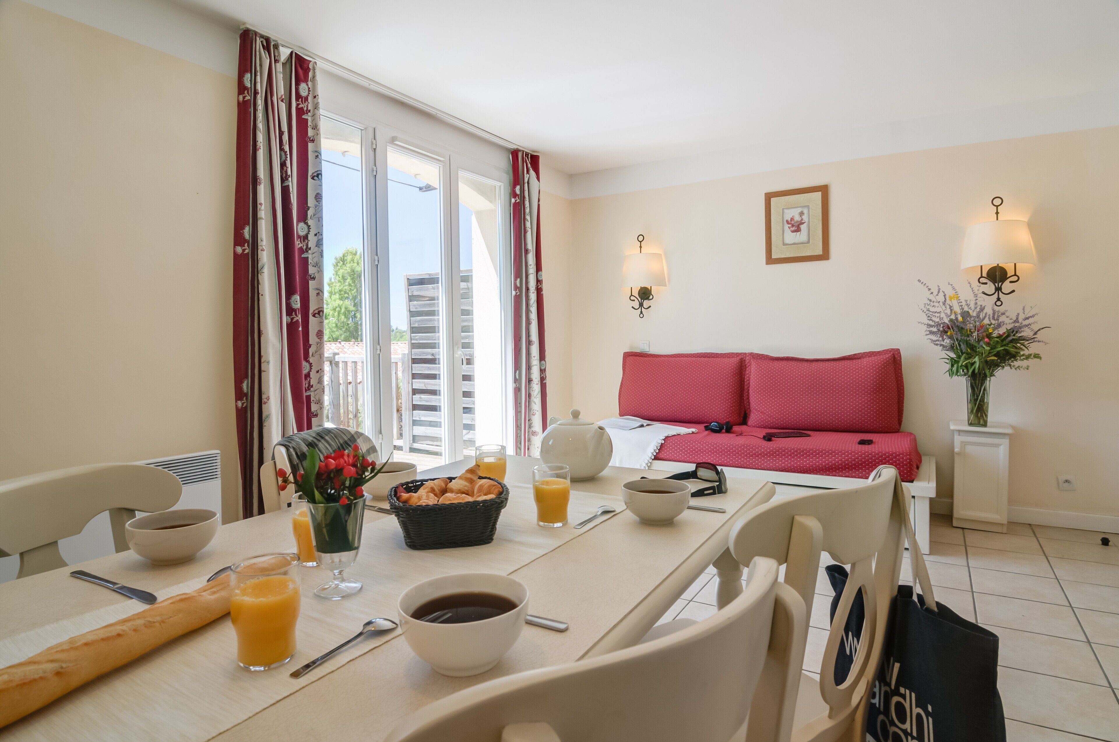 A dining area with a table set for breakfast, including bread, fruit, and beverages.