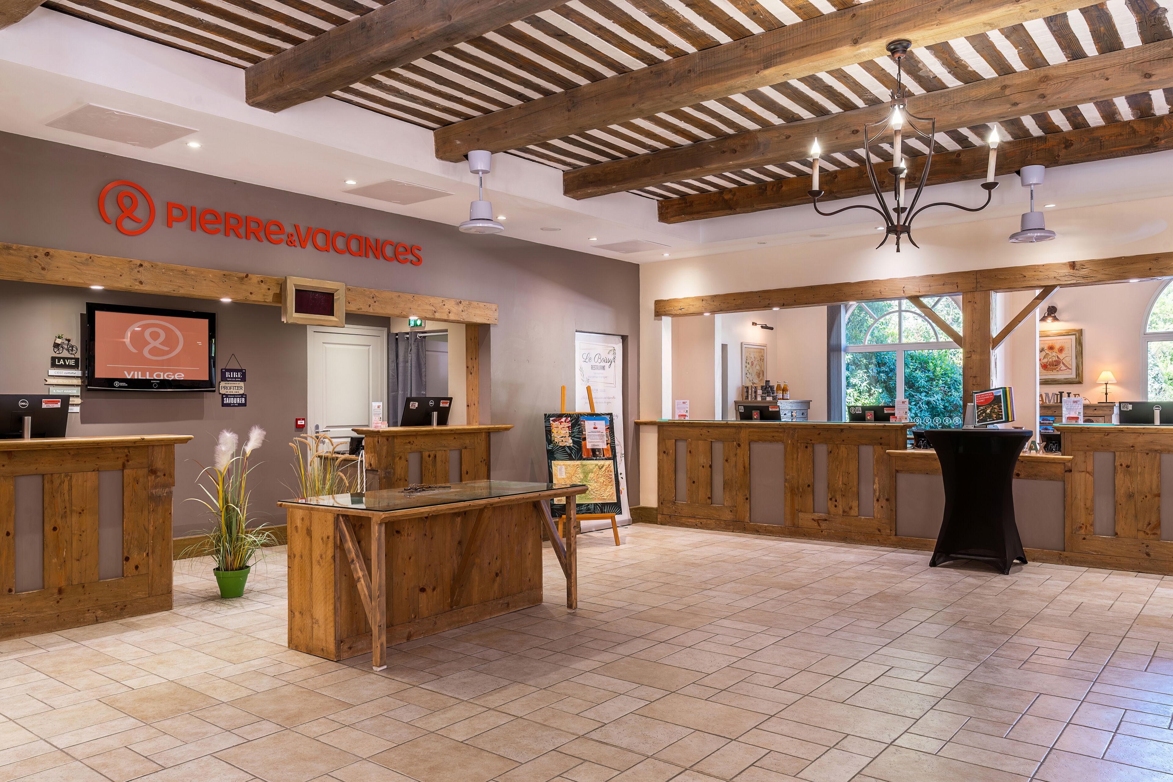 A reception area with wooden furniture, a chandelier, and a sign for 'PERRRE & vacances'.