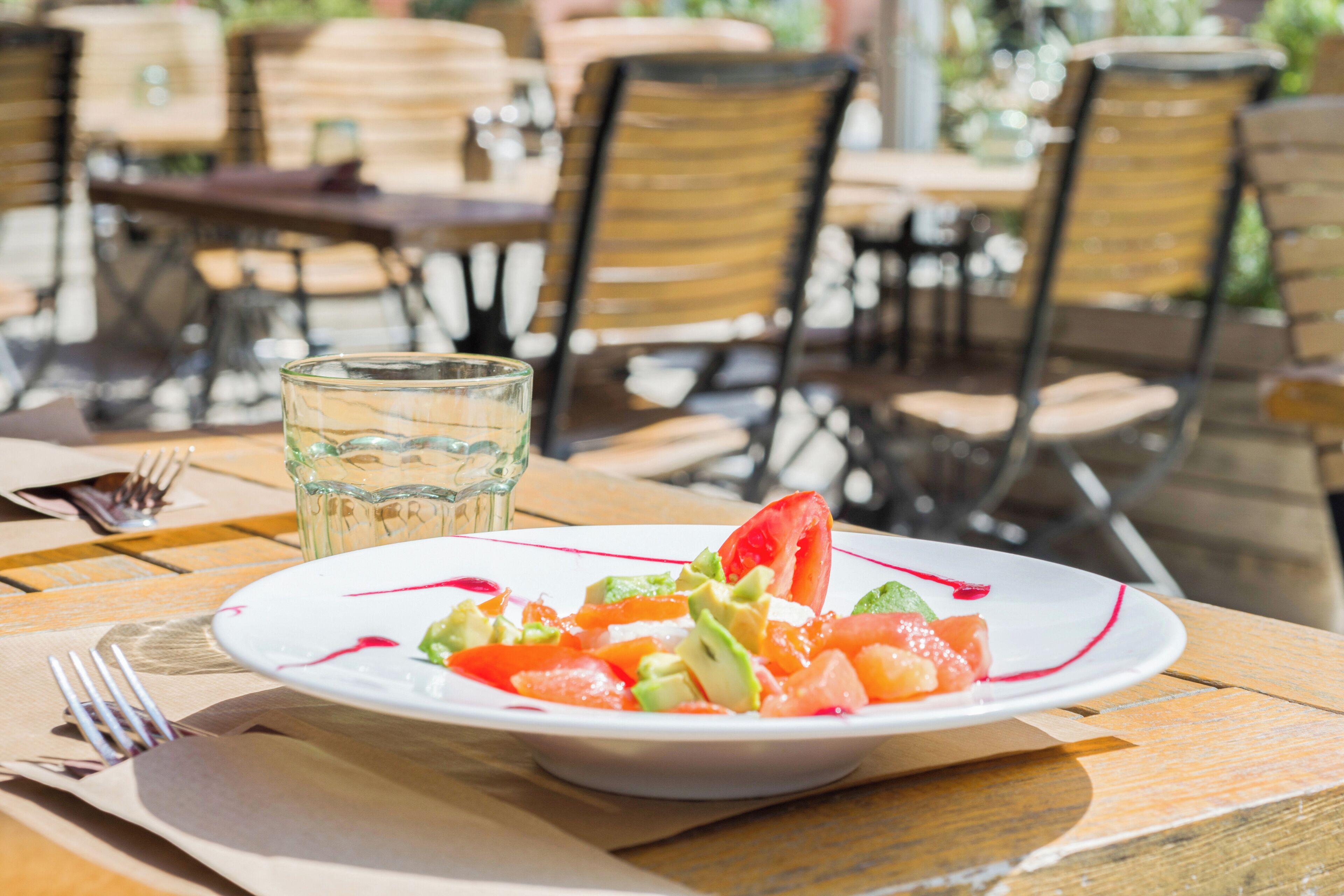 Una mesa con una ensalada de frutas y un vaso de agua.