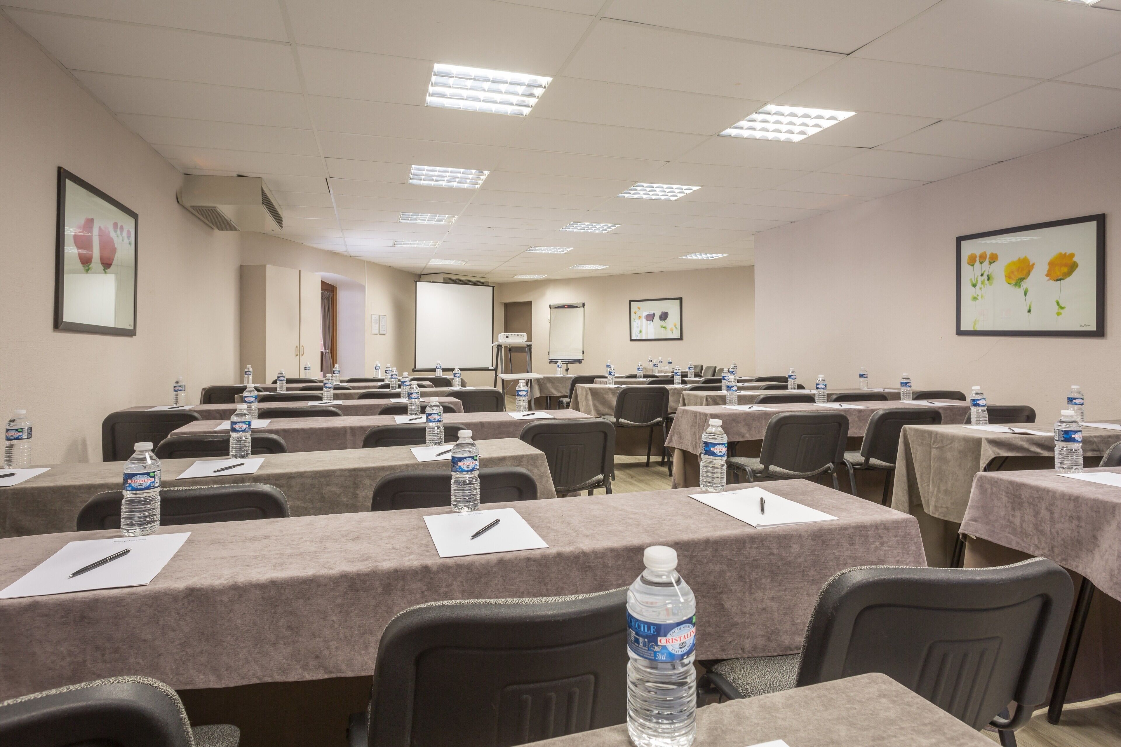 A conference room with tables set up for meetings, equipped with water bottles and pens.