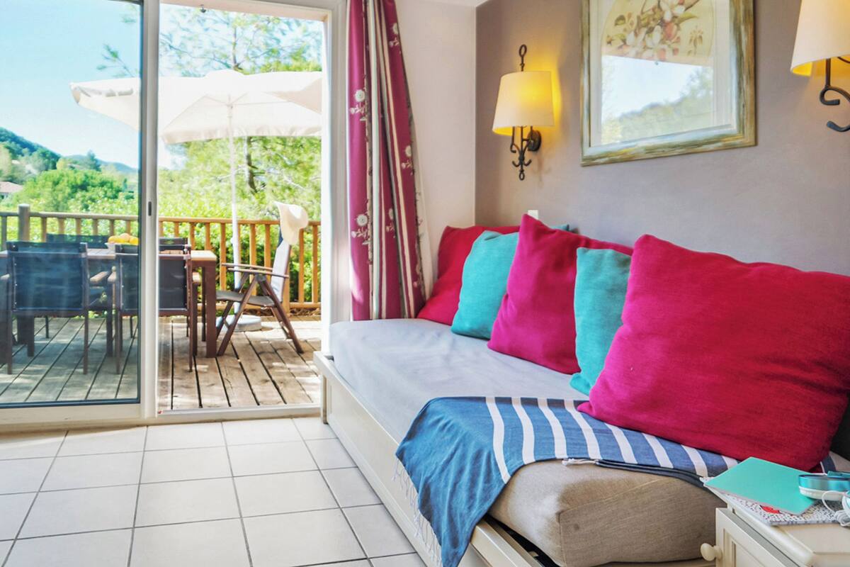 Une chambre à coucher avec un lit, une table de chevet, une lampe et une fenêtre avec des rideaux.