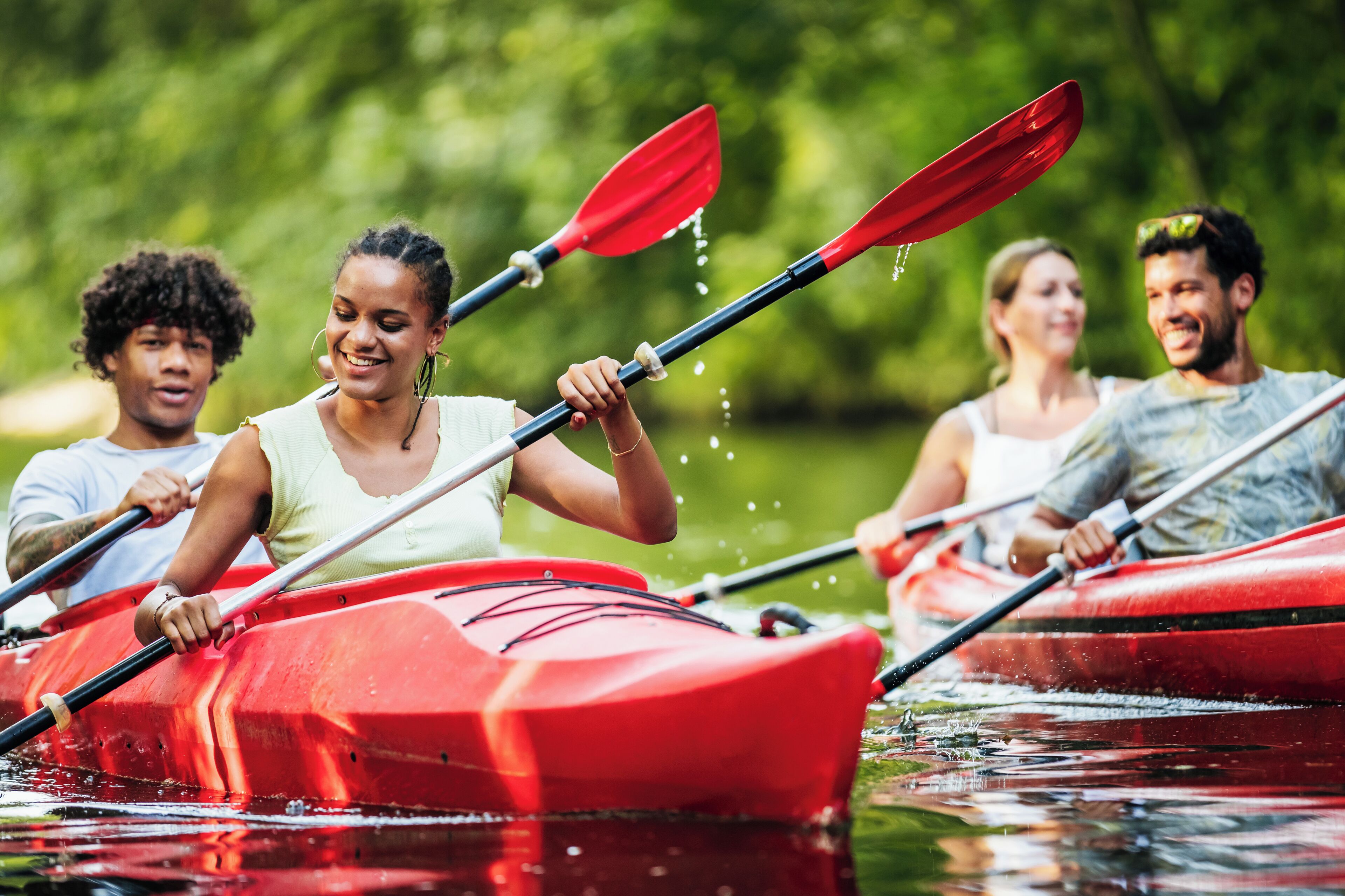 Un gruppo di persone fa kayak in un kayak rosso su un'acqua calma, circondata da vegetazione.