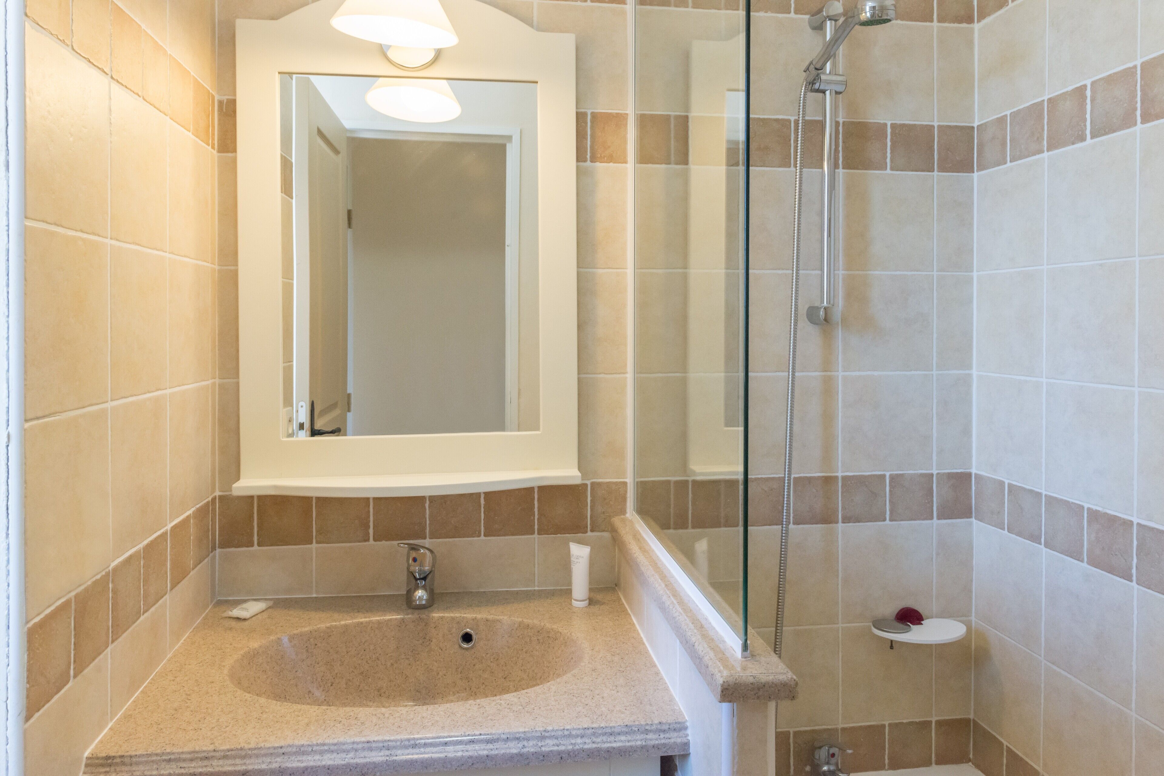 A bathroom with a sink, mirror, shower, and toilet.