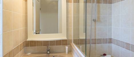 A bathroom with a sink, mirror, shower, and toilet.