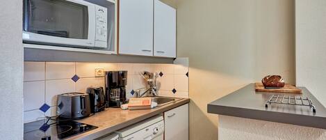 A compact kitchen with a microwave, toaster, coffee maker, and dishwasher.