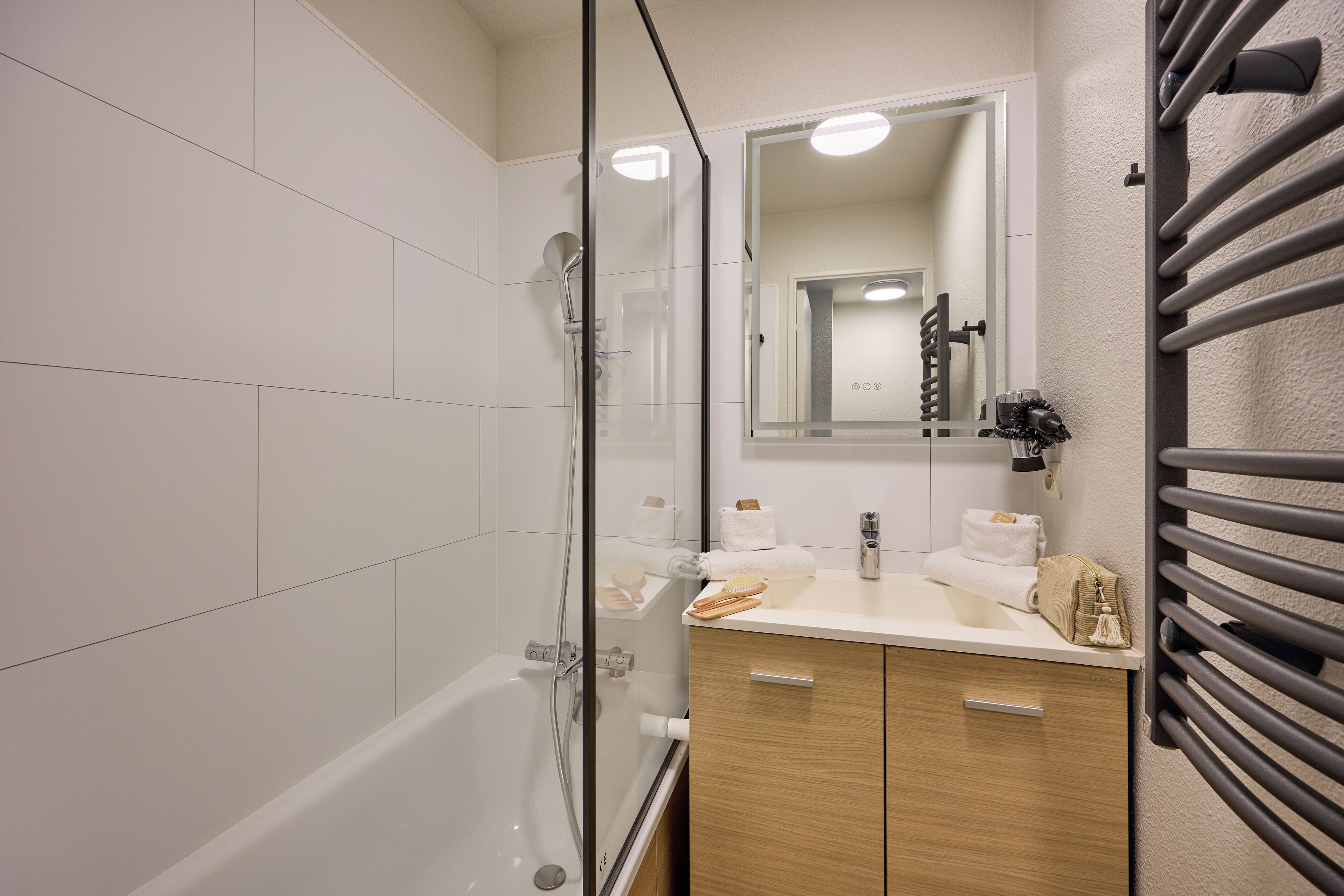 Un baño moderno con cabina de ducha de vidrio, tocador con espejo y un perchero para toallas.