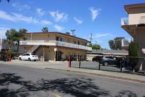 A two-story building with a balcony, a car parked in front, and a fence. - Express Inn (Vallejo)