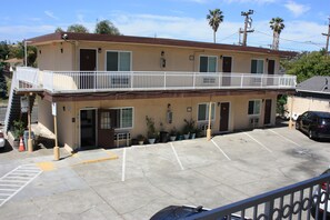 A two-story motel with a balcony on the second floor, a parking lot, and a single-story building in the background. - Express Inn (Vallejo)