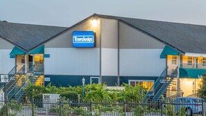 A Travelodge hotel with a sign, two staircases, and a fenced garden area.