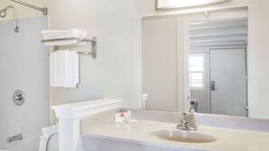 A bathroom with a sink, mirror, towel rack, and shower.