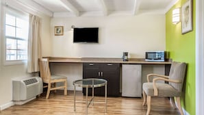 A compact kitchen with a dining area, a flat-screen TV, and a microwave.