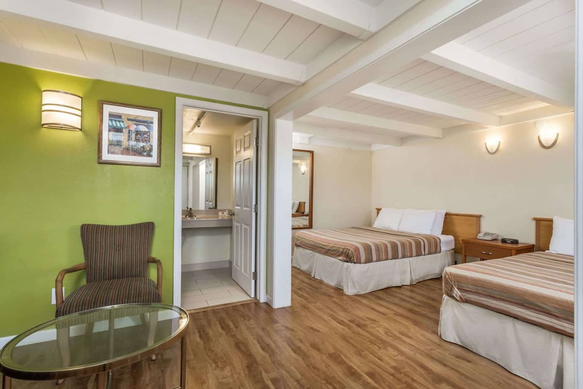 A hotel room with a bed, a chair, a table, and a bathroom visible through an open door.