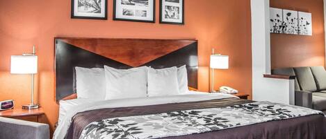 A hotel room with a large bed, two bedside lamps, a chair, and framed pictures on the wall.