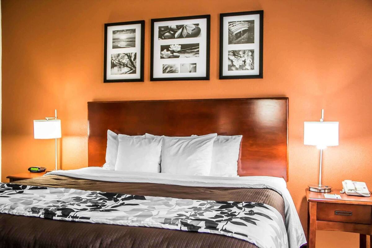 Ein Hotelzimmer mit einem großen Bett, zwei Nachttischlampen, einem Nachttisch mit Telefon und drei gerahmten Bildern an der Wand.