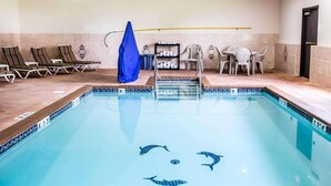 A swimming pool with dolphin designs, lounge chairs, and a small table with chairs.