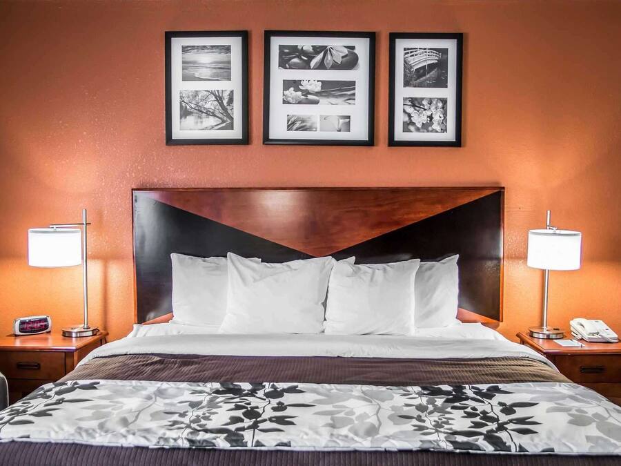 A hotel room with a large bed, two bedside tables, a nightstand, and a wall with three framed pictures.