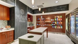 A modern kitchen with wooden cabinets, a central island, and a wall display of packaged goods.
