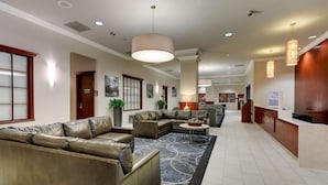 A spacious lobby with leather sofas, a patterned rug, and a reception desk.