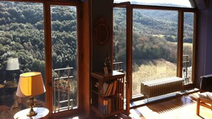 A room with large arched windows offering a view of a forested valley. - Hotel Gattapone (Spoleto)