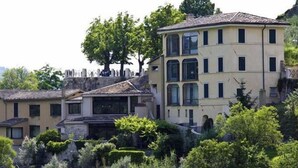 A multi-story building with a central courtyard, surrounded by lush greenery and trees. - Hotel Gattapone (Spoleto)