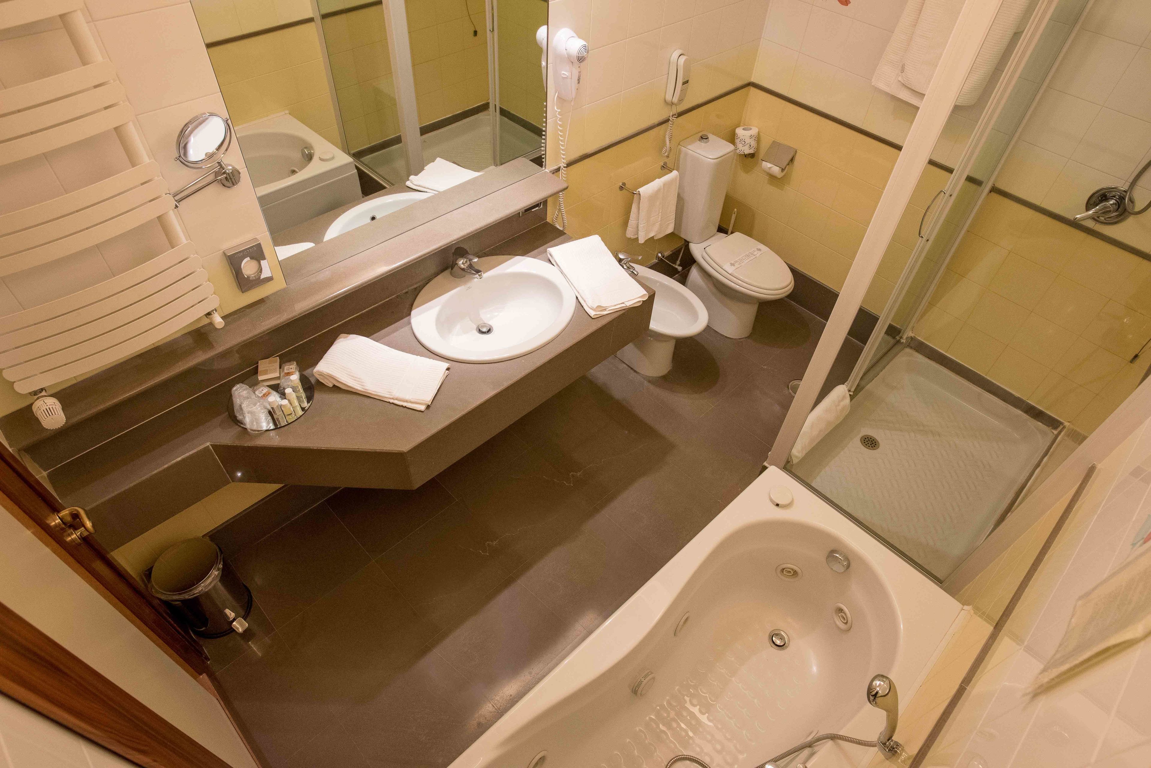 A modern bathroom with a large sink, a toilet, a bathtub, and a shower.