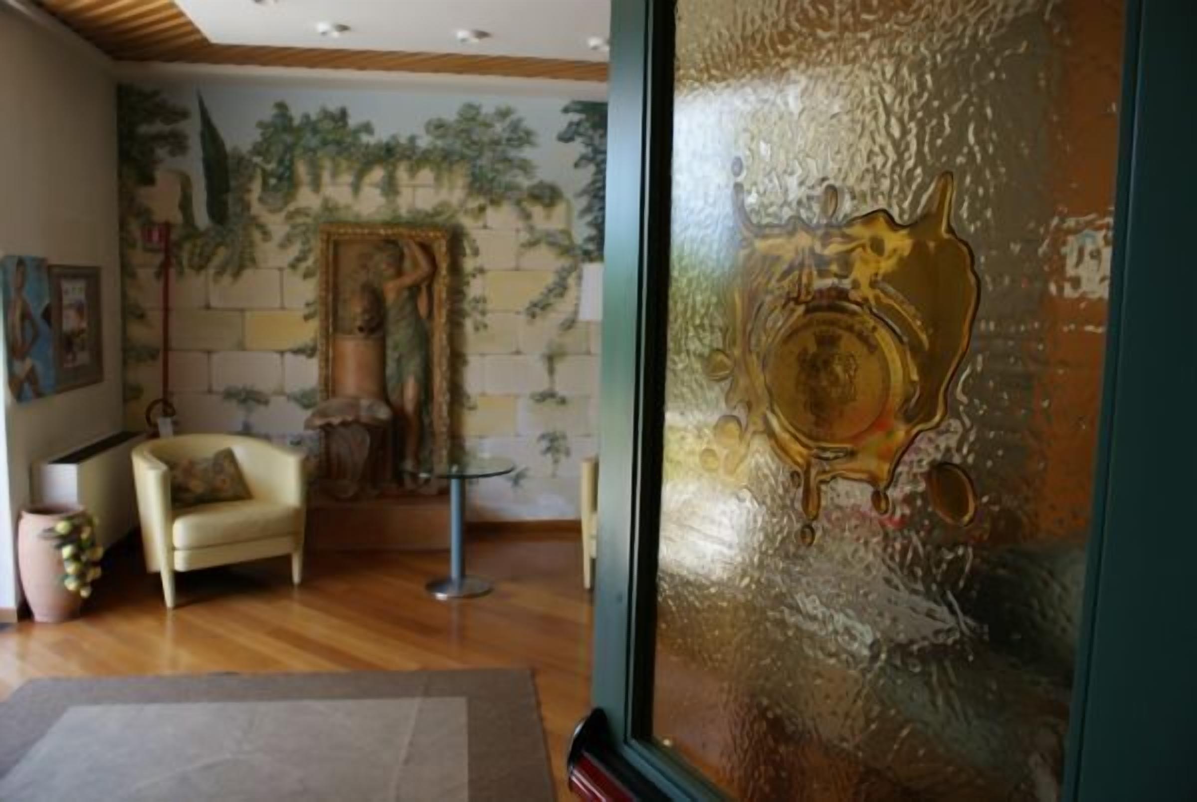 A room with a wooden floor, a beige armchair, a small table, and a decorative wall with a mural.