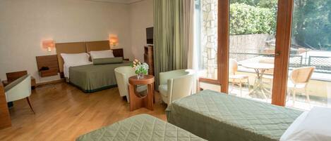A hotel room with two beds, a small table with a vase, a chair, and a view of the outdoor area.