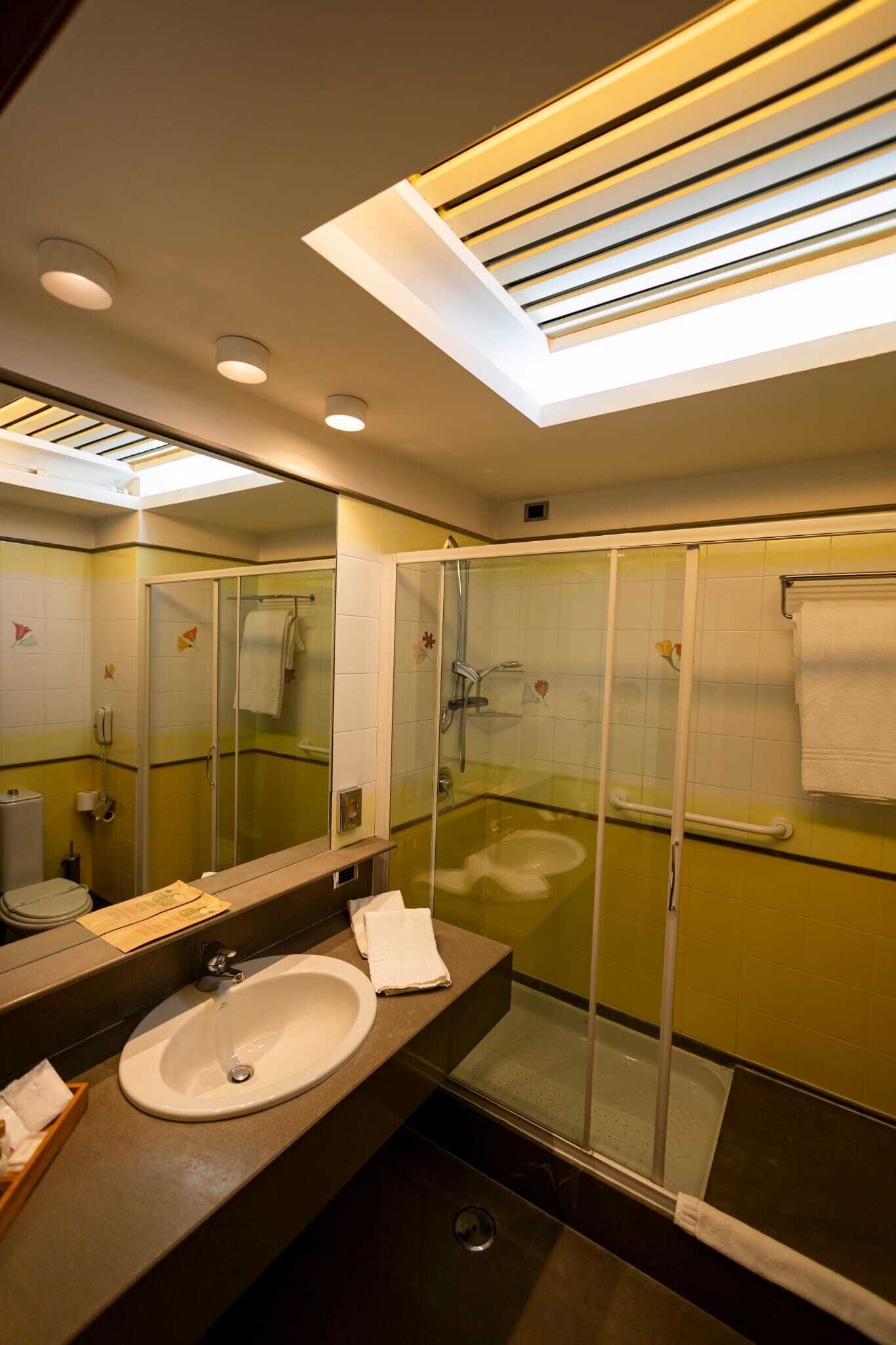 Un baño moderno con ducha de vidrio, un espejo grande y un lavamanos.