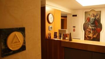 A reception desk with a clock, framed certificates, and a painting on the wall.