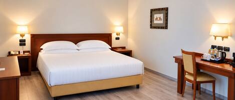 Una habitación de hotel con una cama, mesitas de noche, un escritorio y una silla.