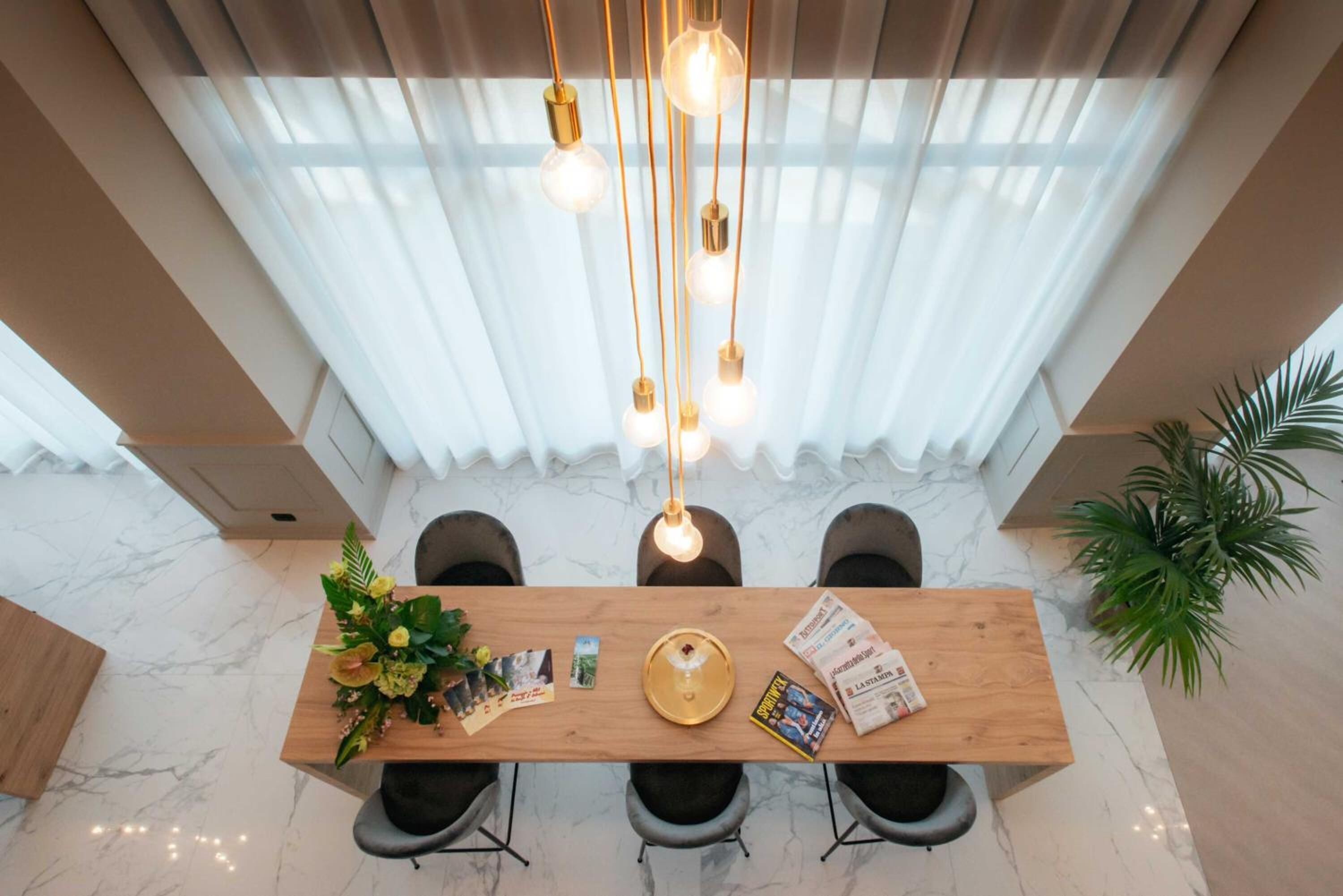 Un comedor moderno con una mesa de madera, cuatro sillas, una araña y una planta en maceta.
