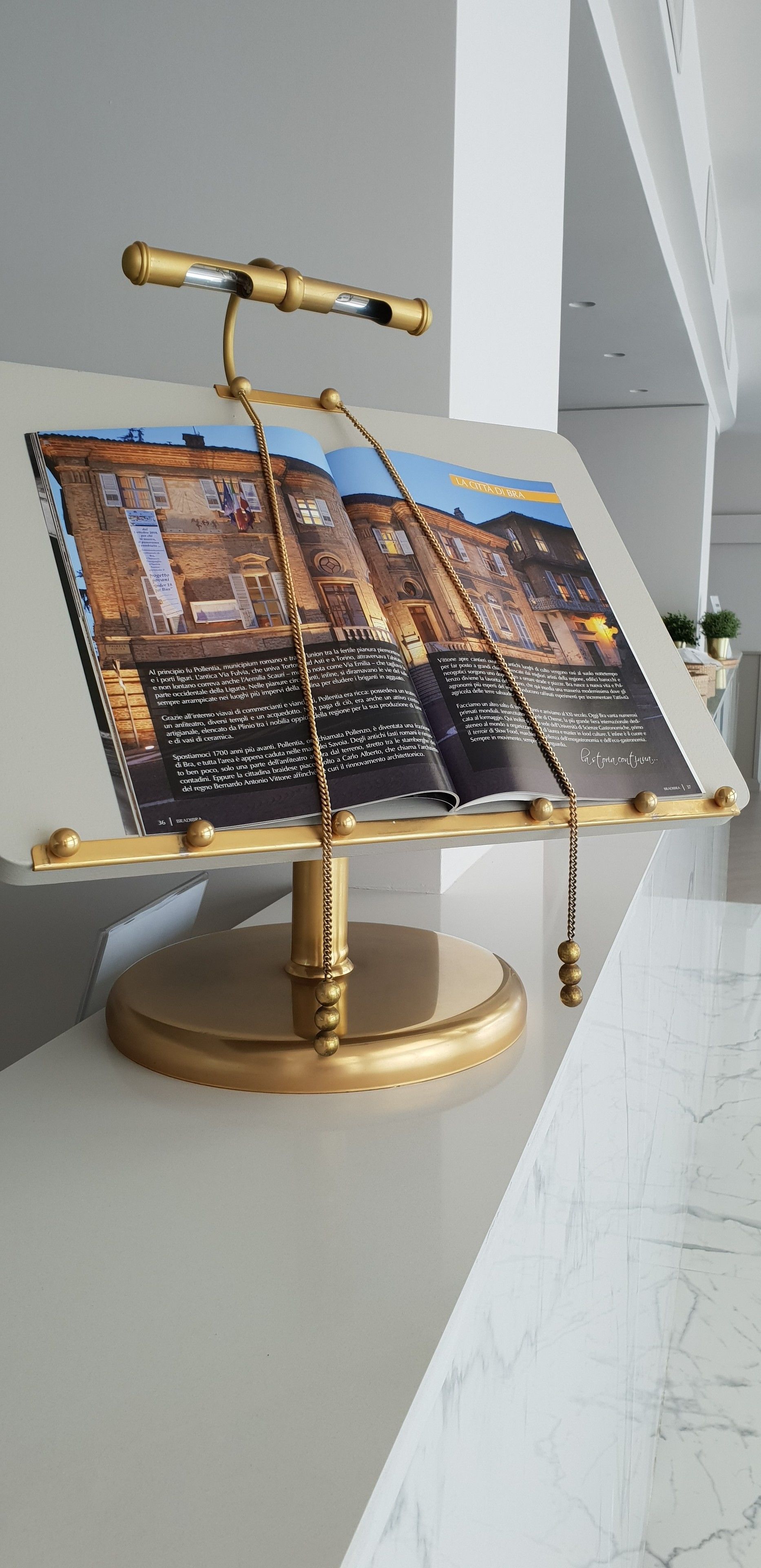 A display stand with a photograph of a building and text, placed on a marble surface.