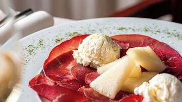A plate with slices of cured meat, cheese, and a scoop of ice cream.