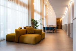 Uma sala de estar moderna com um sofá seccional grande, uma área de jantar com mesa e cadeiras, e uma planta em vaso.