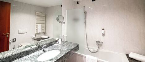 A modern bathroom with a marble sink, a large mirror, a shower with a handheld hose, and a bathtub.