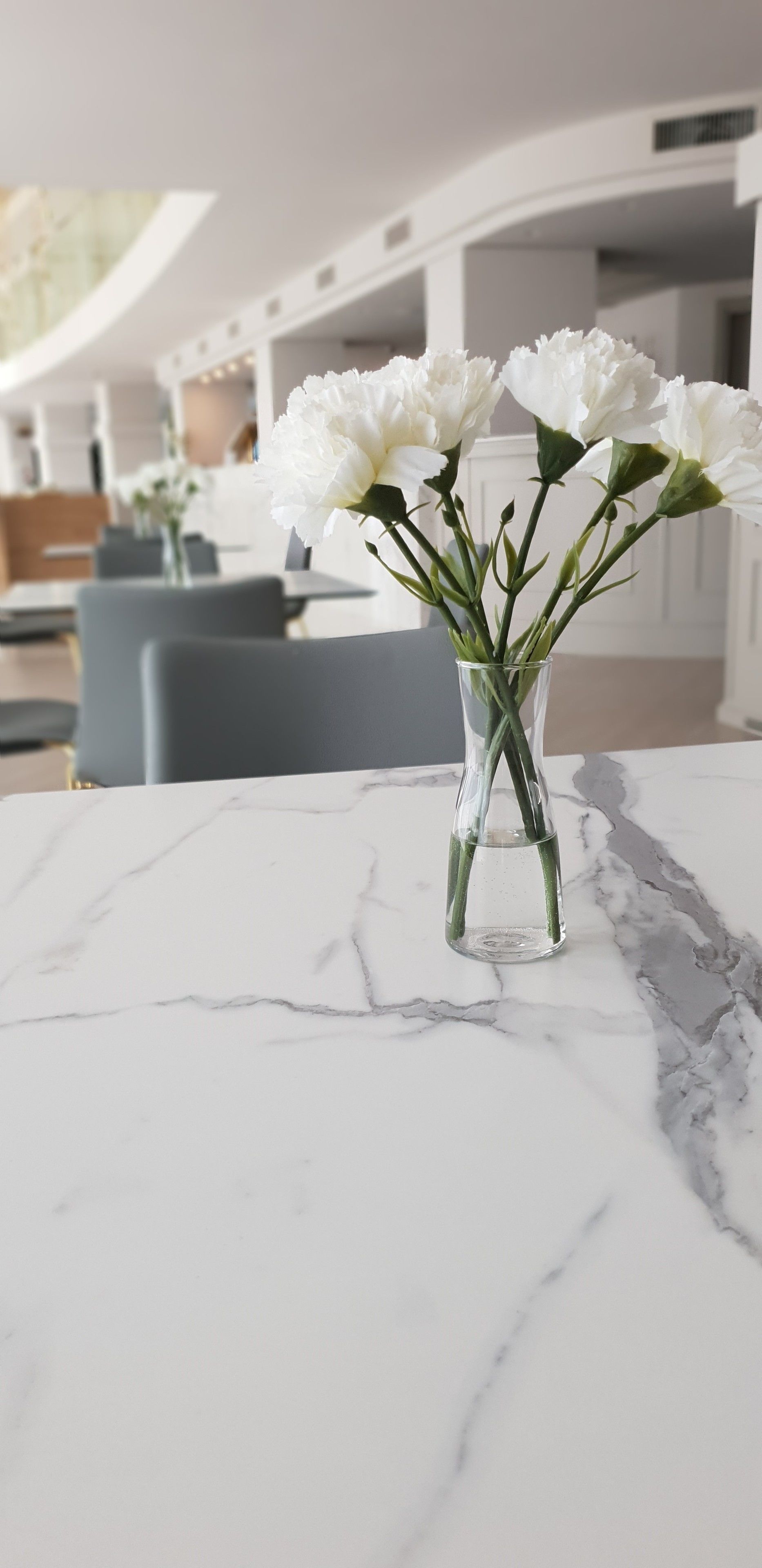A marble table with a clear glass vase containing white flowers.