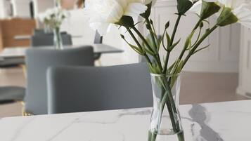 A marble table with a clear glass vase containing white flowers.
