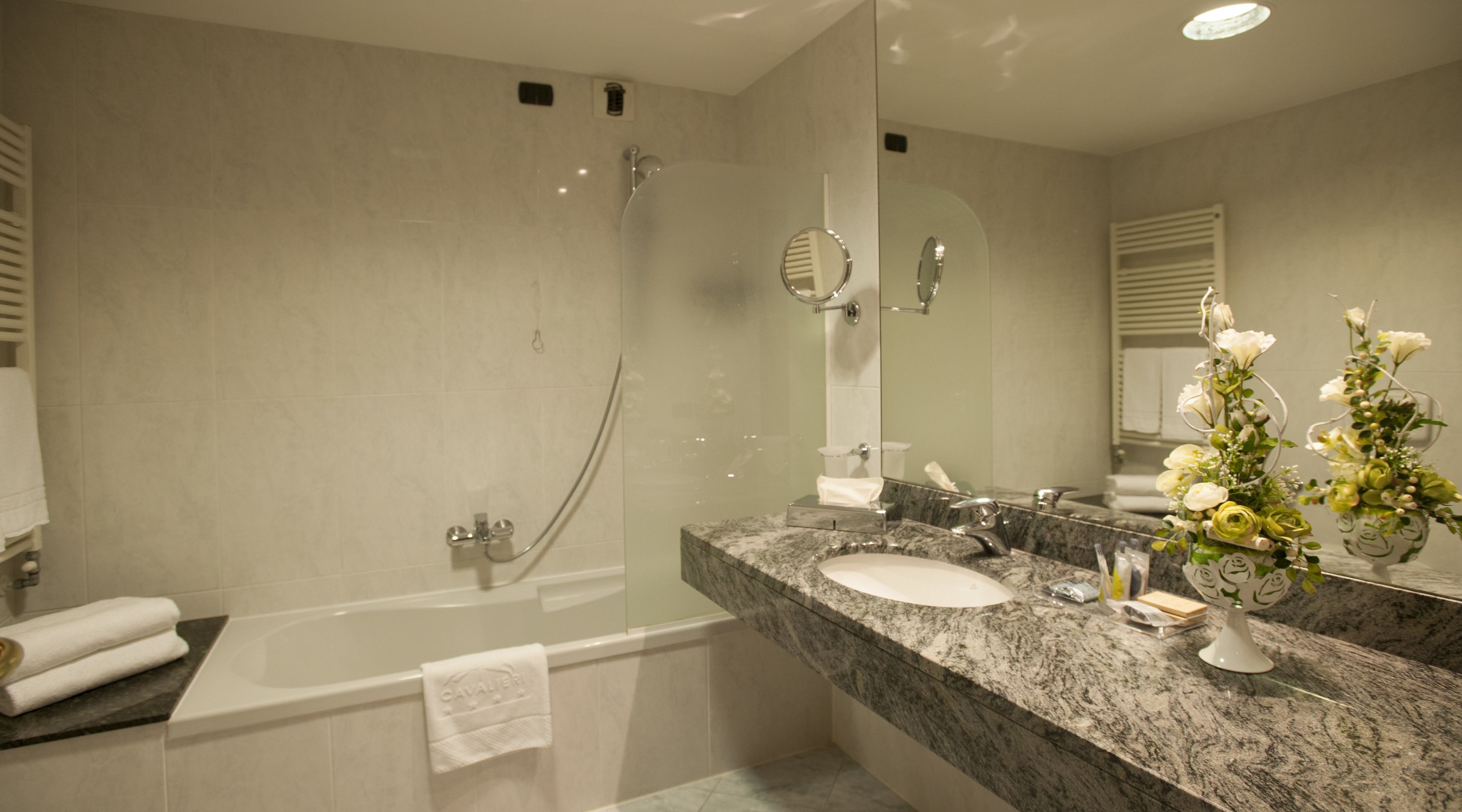 Ein modernes Badezimmer mit Badewanne, Dusche und Waschtisch mit Spüle und Spiegel.