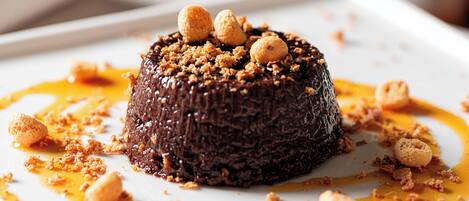 A dessert on a white plate with caramel sauce and nuts.