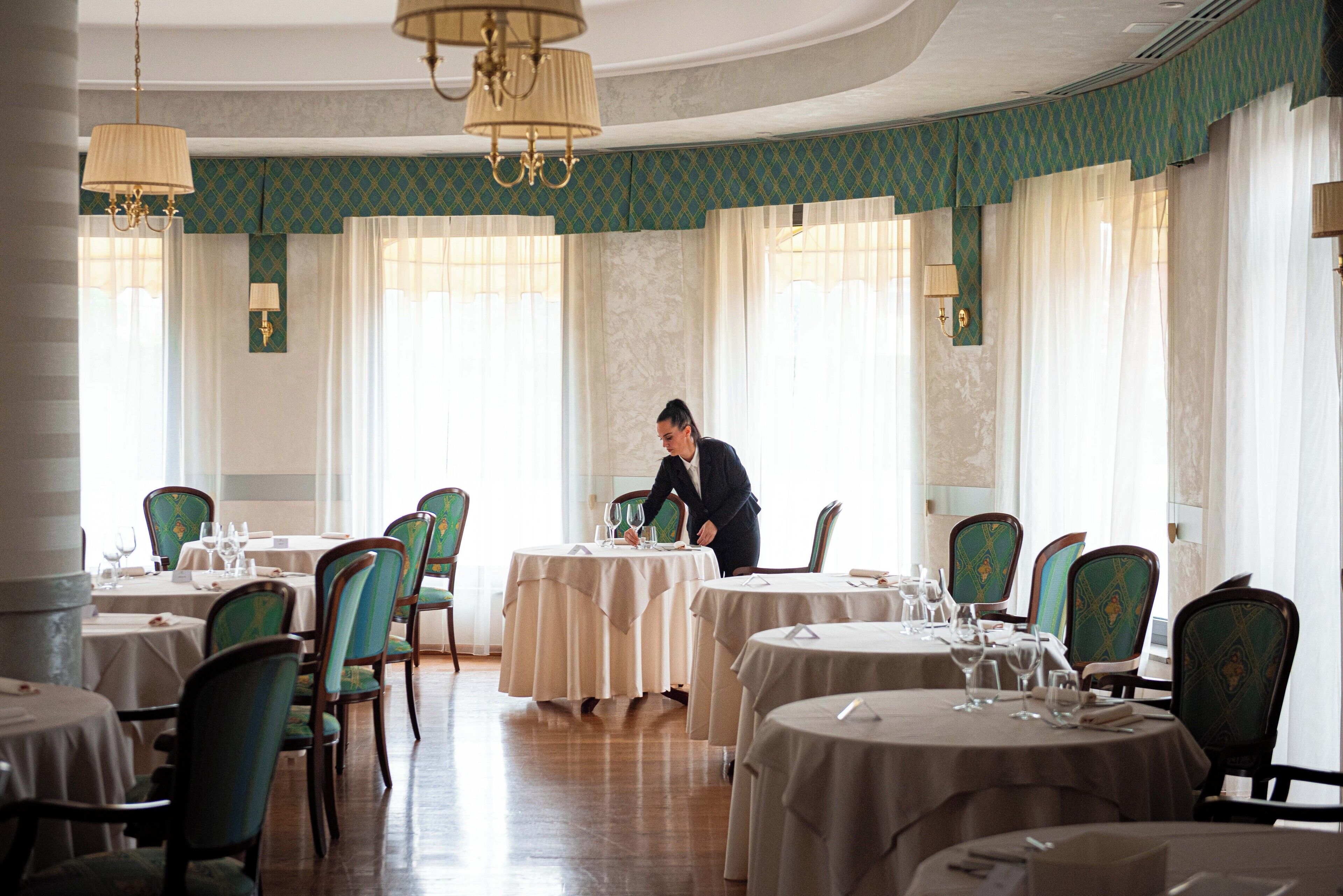 Un comedor con mesas redondas, sillas y candelabros.