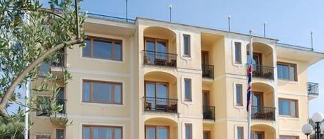 A multi-story hotel with balconies, outdoor seating, and a fountain.