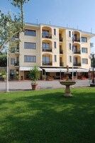 Un h ôtel à plusieurs étages doté de balcons, d’un espace extérieur aménagé et d’une fontaine.
