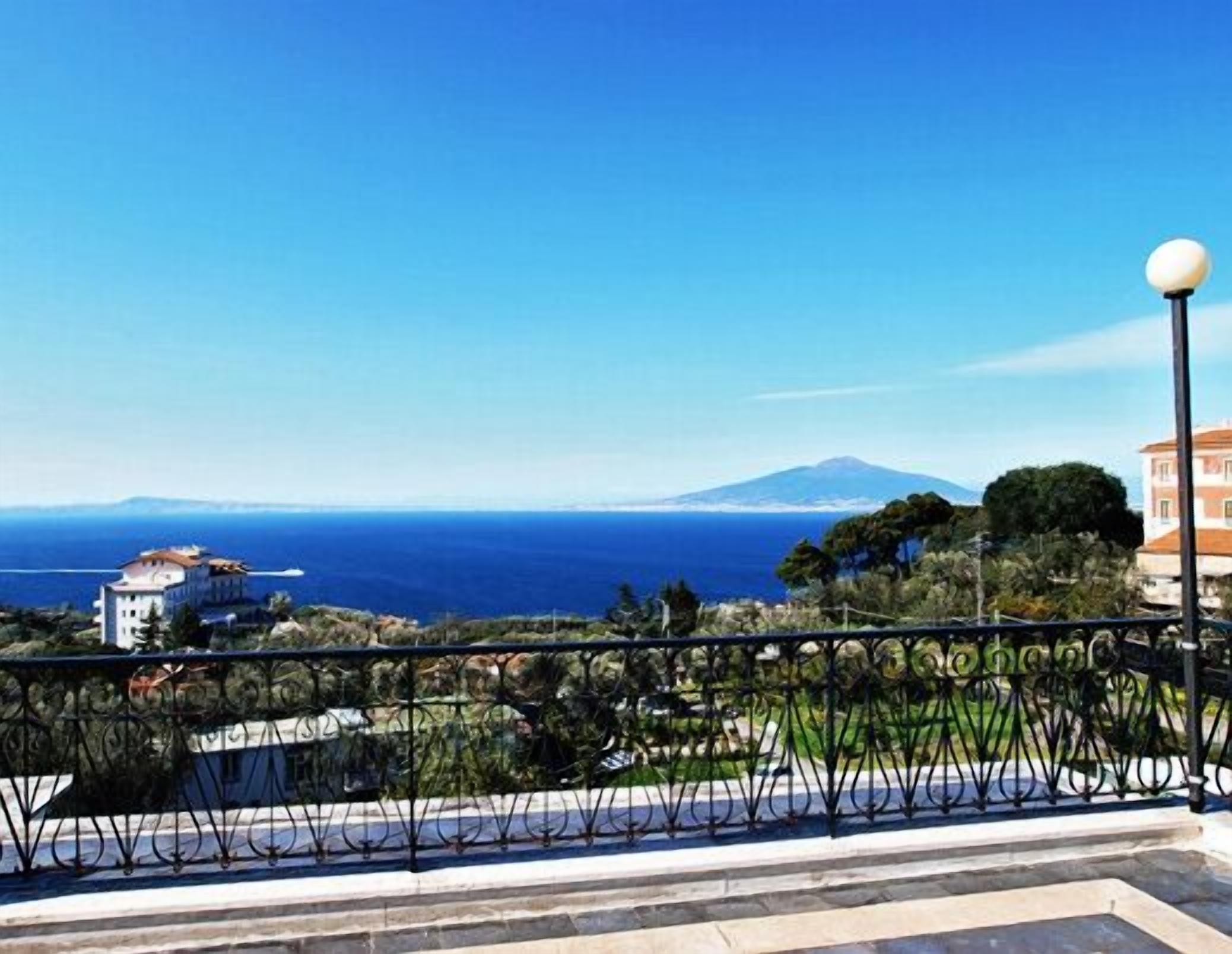 Un balcone con vista sul mare e una montagna all'orizzonte.