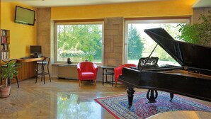 Amplia sala de estar con un piano de cola, ventanas grandes y un rincón de descanso acogedor.
