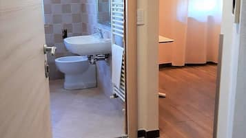 Un baño moderno con lavamanos, inodoro y zona de ducha.