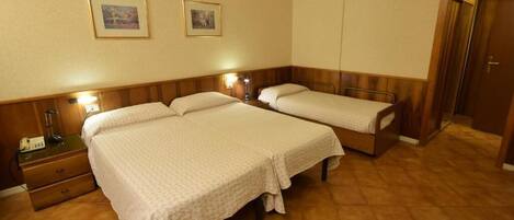 Une chambre d’hôtel avec deux lits, une table de chevet avec une lampe et une porte en bois.