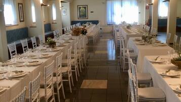 A long dining hall with white tables and chairs, arranged in a symmetrical layout.