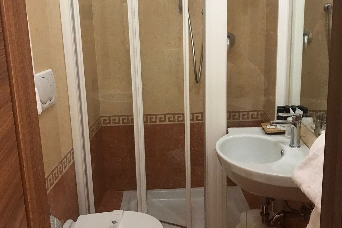 Un baño con ducha de vidrio, lavamanos e inodoro.