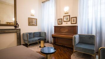 Una sala de estar con un piano, dos sillones, un sofá y una mesa redonda.