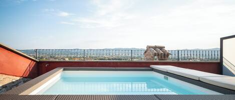 Una piscina en la azotea con vistas despejadas al paisaje urbano y montañas a lo lejos.